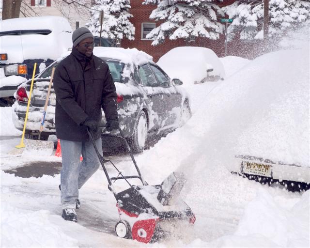 A Warren Street Resident Using a Snow Blower. Credit, Bernie Photos